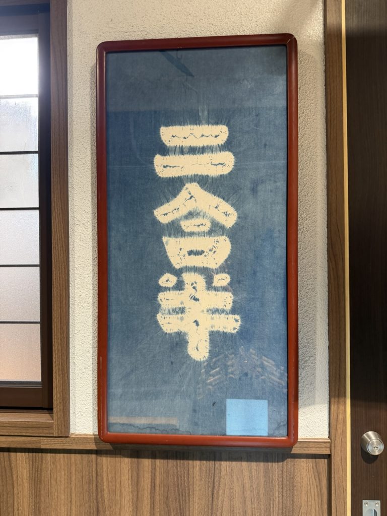 額装された藍染めの「二合半」の暖簾